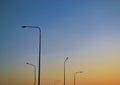 Five tall lampposts against a gradient evening clear sky at sunset