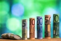 Five, ten, twenty, fifty and one hundred euro rolled bills banknotes, with euro coins on green blurred bokeh background. Royalty Free Stock Photo