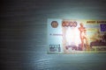 Five thousand rubles banknote lies on a table lit by a ray of light