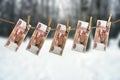 Five thousand russian rouble banknotes hanging on a clothesline with clothes pegs on blurred winter forest background Royalty Free Stock Photo