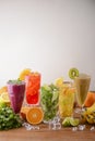 Five tropical mixed drinks, orange, lemon, kiwi fruit, mint, lime and raspberries cocktails served on wooden table.