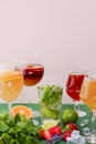 Five tropical mixed drinks, orange, lemon and raspberries cocktails over bright pastel green background.