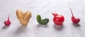 Five ugly vegetables are standing in row on grey concrete background.