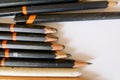 Five very short, soft graphite pencils in a group with other pencils on white ground.