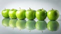 Five vibrant green apples arranged in a neat row, their reflections mirrored on a sleek surface, creating a visually appealing and Royalty Free Stock Photo