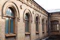 Five vintage arched windows in a wall of yellow bricks. Green - the colors of sea wave glass in a maroon dark red wooden Royalty Free Stock Photo