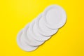 Five white eco-friendly cardboard plates lie on yellow colored paper background. Top view. Close-up. Mock-up Royalty Free Stock Photo