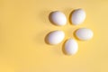 Five white eggs are lying in circle on a yellow background with copy space. Royalty Free Stock Photo