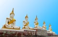 Five white and gold Buddha statue sitting on painted seat base with blue sky background Royalty Free Stock Photo