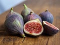 Five whole and one cut figs in a group close-up on a wooden table