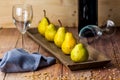 Five Williams pears on a wooden plate with wine glasses and seeds on a wooden table Royalty Free Stock Photo