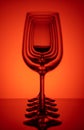 Five wine glasses in row concentric silhouette one full glass on red-orange background Royalty Free Stock Photo