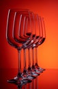 Five wine glasses in row perspective one full glass on red-orange background Royalty Free Stock Photo