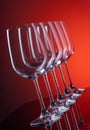 Five wine glasses in row tilted in perspective on red background Royalty Free Stock Photo