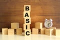 Five wooden cubes stacked vertically on a brown background make up the word BASIC. Royalty Free Stock Photo