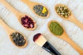 Five wooden spoons with various types of tea and make-up brush. Green tea, matcha, chamomile, hibiscus and herbal tea