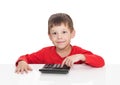 The five-year boy sitting at a white table and presses the button calculator Royalty Free Stock Photo