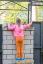 Five-year girl climbed on brick fence and looks for him
