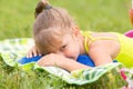 Five-year girl lies on a bed on green meadow and artfully looks aside
