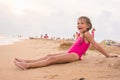 Five-year girl sits on beach in the evening sea coast on a cloudy day