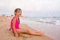 Five-year girl sits on beach and seaside fun looking into the distance Royalty Free Stock Photo