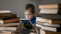 Five year old boy in glasses reading a book with a stack of books next to him. Smart intelligent preschool kid choosing books to Royalty Free Stock Photo