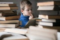 Five year old boy in glasses reading a book with a stack of books next to him. Smart intelligent preschool kid choosing books to Royalty Free Stock Photo