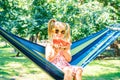 Five-year-old girl with a watermelon sits on a hammock in the park