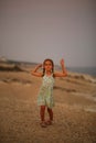 Five year old girl in a summer dress dancing on a sunset beach Royalty Free Stock Photo