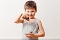 A five-year-old Russian boy dips a rolled pancake into liquid honey on a white background. Russian Maslenitsa holiday