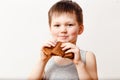 A five-year-old Russian boy in a gray t-shirt eats an oil pancake on a white background. Maslenitsa