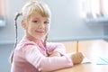 Five years old blonde girl sitting at classroom and writing