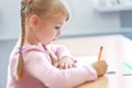 Five years old blonde girl sitting at classroom and writing