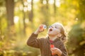 Five years old caucasian child girl blowing soap bubbles outdoor at sunset - happy carefree childhood.Fall seasom