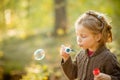 Five years old caucasian child girl blowing soap bubbles outdoor at sunset - happy carefree childhood.Fall seasom Royalty Free Stock Photo