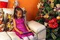 Five-year-old Colombian Afro-descendant Latina girl sitting on the sofa next to the Christmas tree checking her tablet