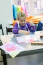 Five years old girl making drawing on the water. Ebru art with oil paints by water surface Royalty Free Stock Photo