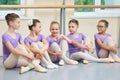 Five young ballerinas sitting on the floor.