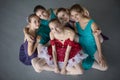 Five young ballerinas sitting on the floor and looking to the ca