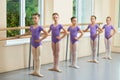 Five young ballerinas standing in pose.