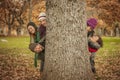 Five young people behind a big tree.