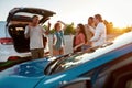 Five young well-dressed friends dancing to music and smiling together outside on a parking site near their cars with a Royalty Free Stock Photo