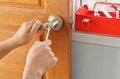 Fix the metal door knob on the wooden door with two handles, screwdriver Red metal mechanic box Mechanic work in the house Install Royalty Free Stock Photo