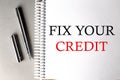FIX YOUR CREDIT text on a notebook with pen on grey background Royalty Free Stock Photo