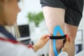 Fixation of kinesio tape on the patient`s leg.