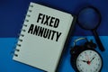 Fixed Annuity text written on notebook paper with magnifying glass and alarm clock Royalty Free Stock Photo