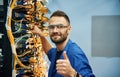 Fixed, with thumbs up. Young man is working with internet equipment and wires in server room Royalty Free Stock Photo