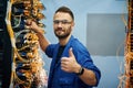 Fixed, with thumbs up. Young man is working with internet equipment and wires in server room Royalty Free Stock Photo