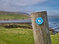 Fixed to a wooden post on the coast, a blue and white Access Shetland sign near Sandwick in Shetland, UK