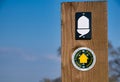 Fixed to a wooden post on a stile, a direction marker and white acorn logo of a Natural England National Trail